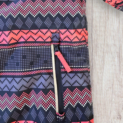 Veste de ski fille Crivit 7-8 ans bleu marine à motifs géométriques roses, blancs et violets, avec capuche, poches zippées et passe-pouces.